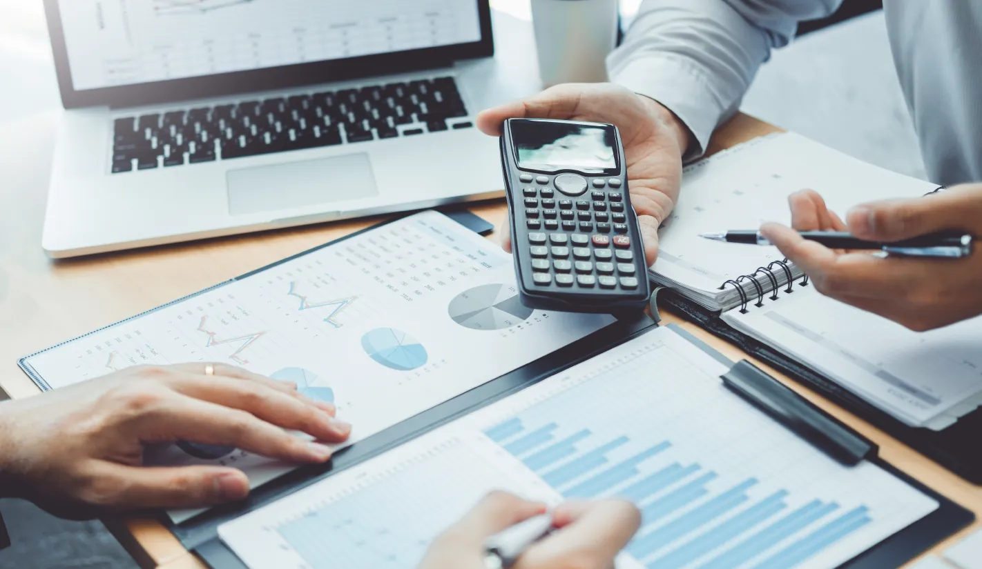 Business meeting with financial charts, calculator, and laptop – defense project financing and capital structuring